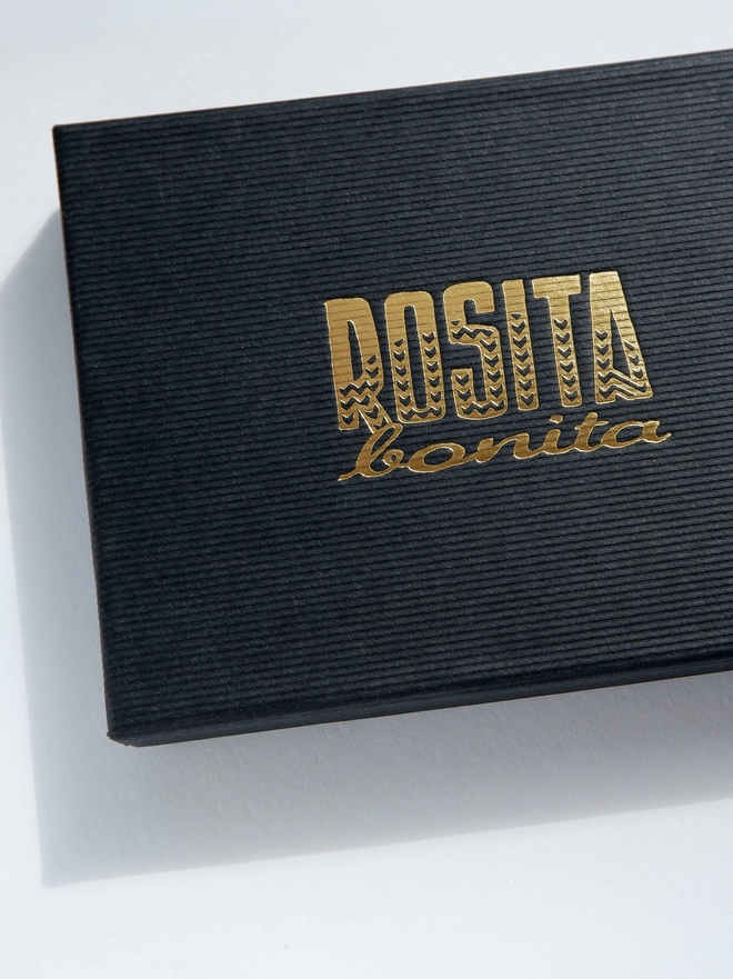 black ribbed paper boxes with Rosita Bonita logo printed in gold