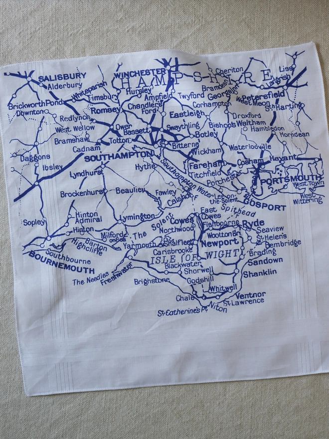 A Mr.PS Solent map hankie printed in blue laid flat on a linen tablecloth