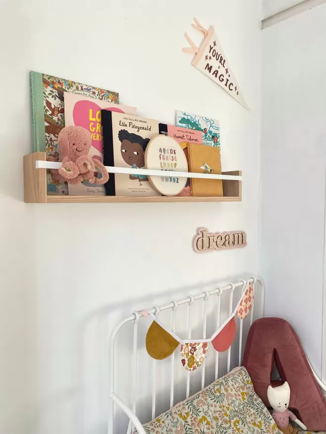 Large bookshelf by Autumn's Corner seen above a bed with 'Dream' sign made in wood.