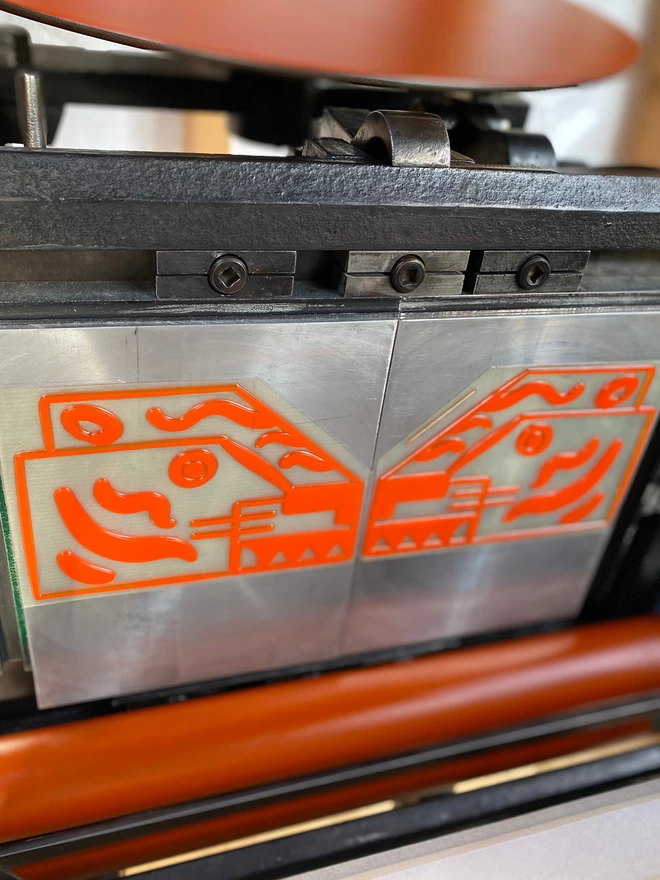 Tiger head printing plate on traditional letterpress machine with orange ink on rollers. 