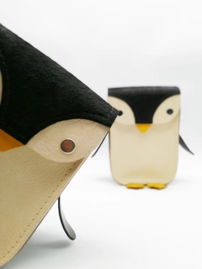 Front and partial front view of two Penguin bags, one leaning in to the picture from the side.