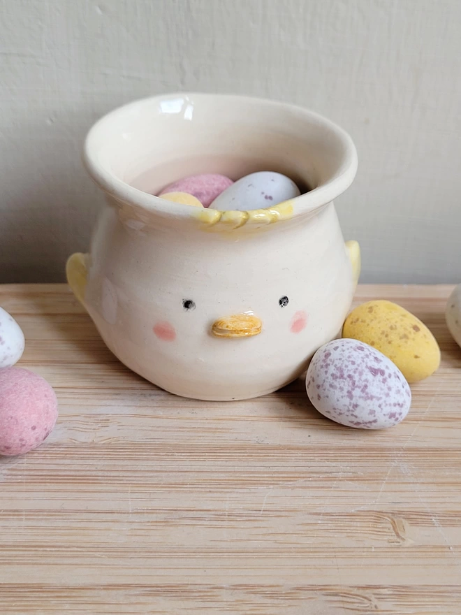 an Easter chick egg up with cute kawaii expression an pink cheeks with mini chocolate eggs in light pastel colours