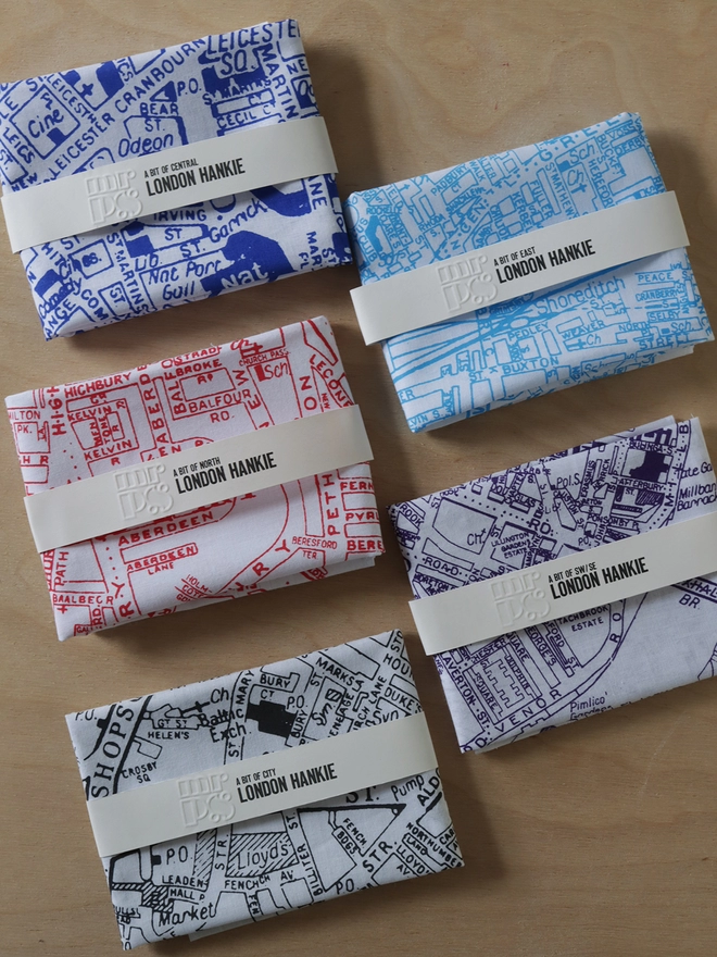 The 5 options of parts of London map hankies laid on a table