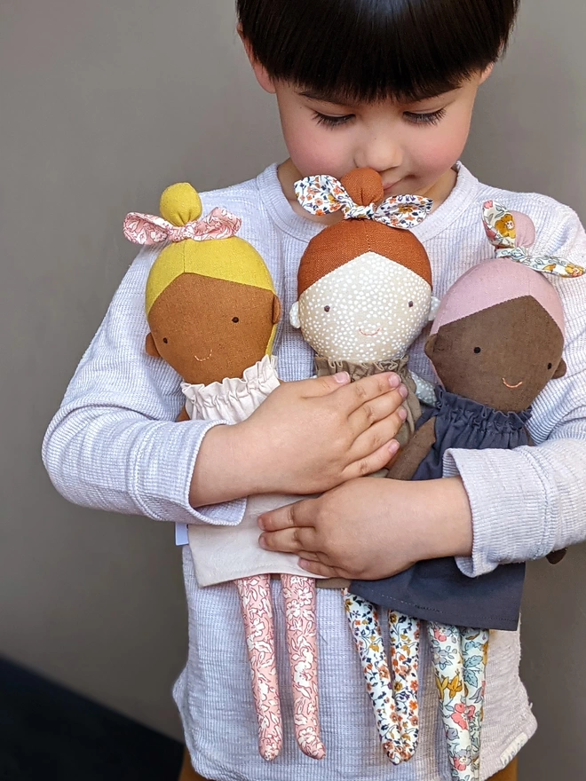 boy holding girl dolls with different skin tones 