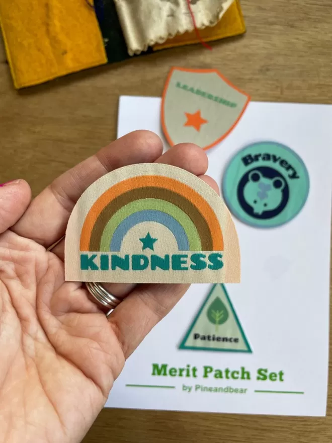A hand holding a kindness merit path with a rainbow design.
