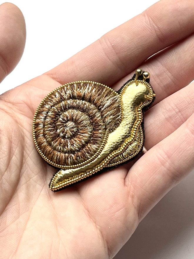 Golden snail brooch on hand