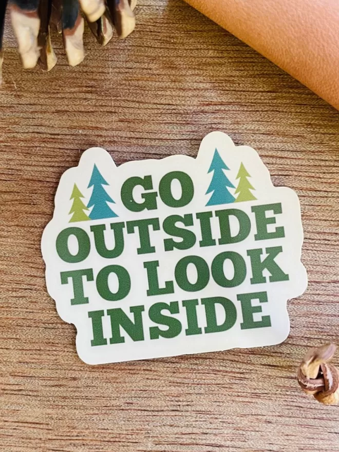 Go Outside To Look Inside Vinyl Sticker on a wooden background