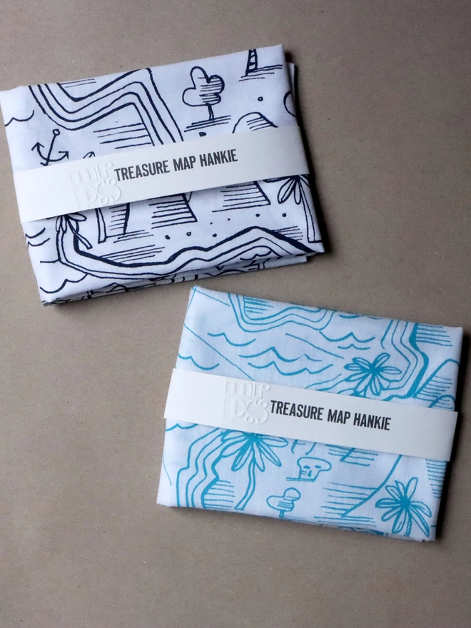 two folded treasure map hankies, one in midnight blue and one in aqau