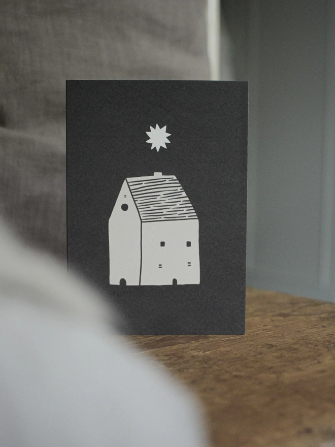 Black and white greeting card with illustration and the words starry night written on it stood up on a wooden surface
