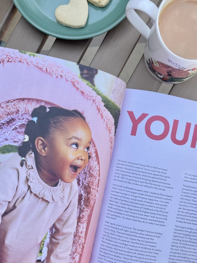 Photograph showing a young child excited by a museum exhibit inside Sonshine magazine issue 21 on a garden table with a cup of tea 
