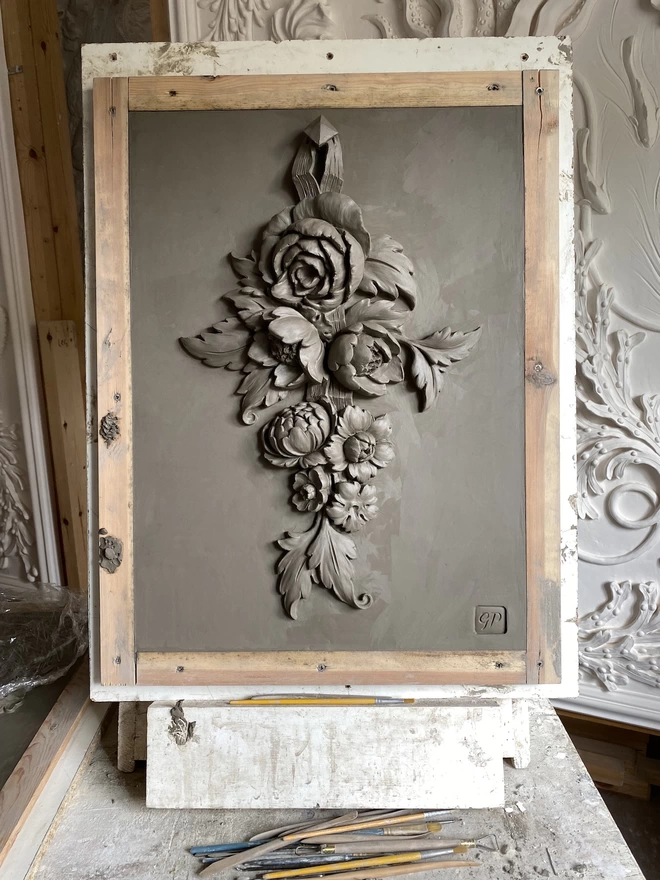 Clay model of flower sculpture on easel with modelling tools
