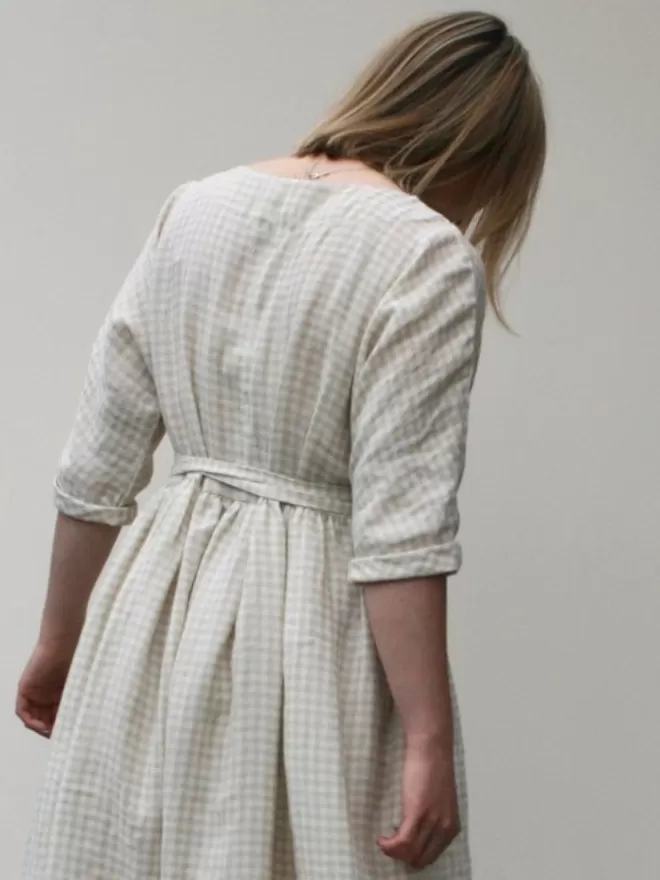 Linen dress in a neutral oatmeal check. Scooped neckline, gathered skirt and elbow length sleeves. Mid calf length and deep side seam pockets.