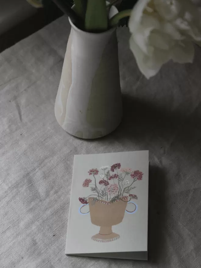 Queen Annes Lace on greetings card next to blooming tulip in vase.