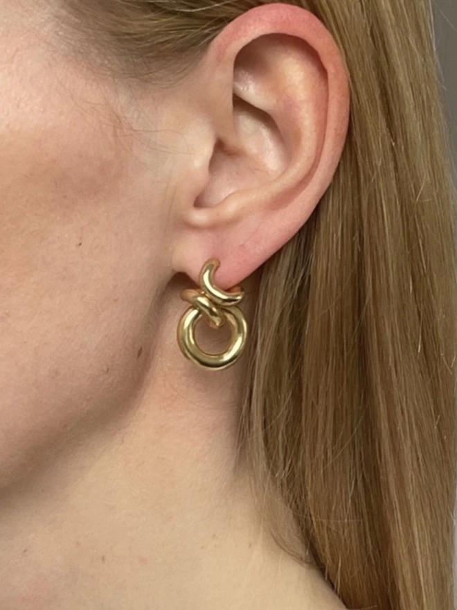 A model wearing a gold modern hoop earring