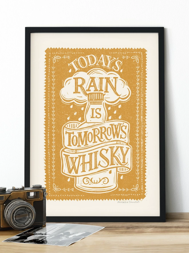 yellow scottish whisky print in a black frame with a vintage camera