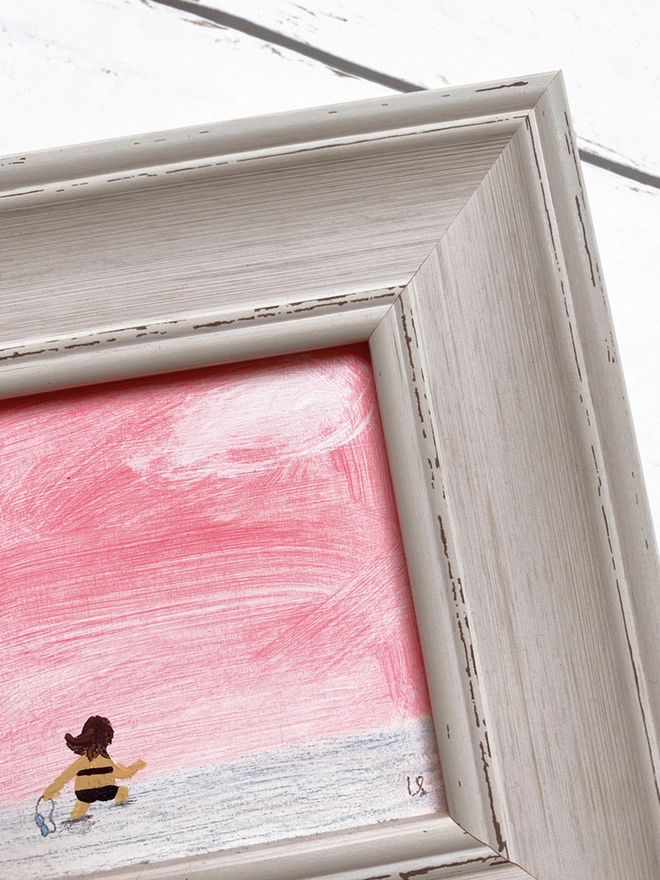 detail of painting of sunset and swimmer in chunky pale grey frame