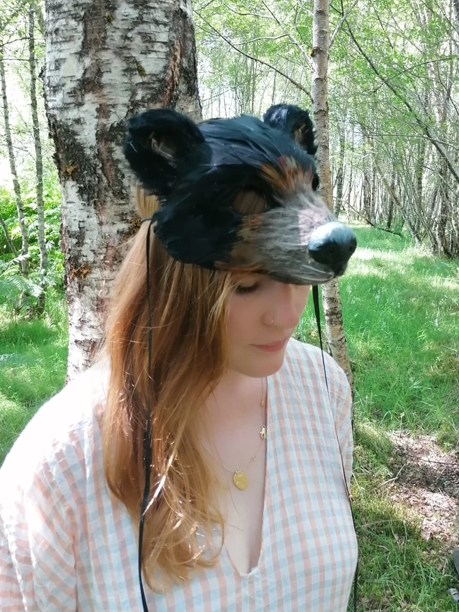 A woman wearing a luxury black bear party mask atop her head as a headdress