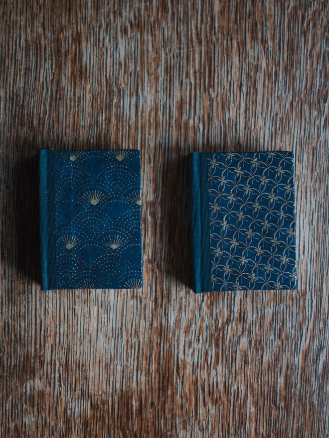 Two miniature hardback journals, with assorted navy and gold printed covers