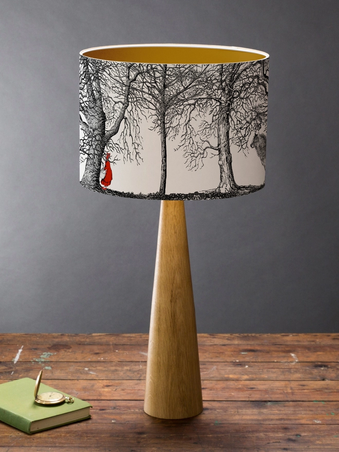 Drum Lampshade featuring Red Riding Hood on a wooden base on a shelf with books and ornaments
