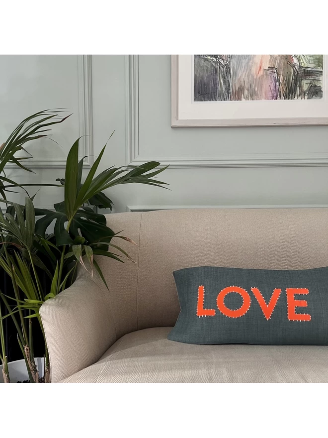 A cushion from the same range saying LOVE on a sofa.