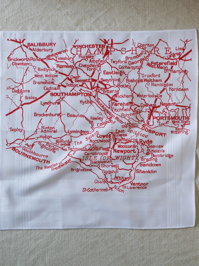 A Mr.PS Solent map hankie printed in red laid flat on a linen tablecloth
