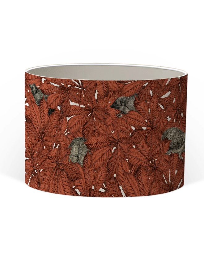 Drum Lampshade featuring hedgehogs in autumnal russet red leaves with a white inner on a white background