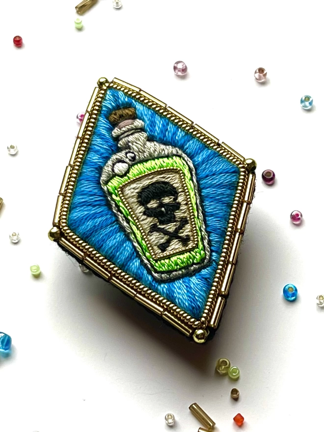 Poison Bottle Brooch on background with beads