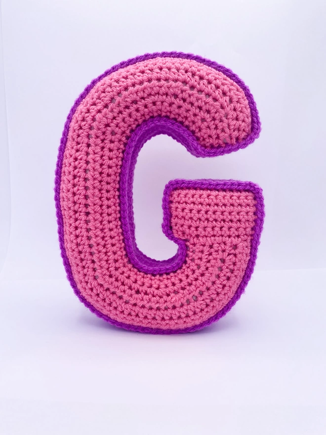Crochet cushion shaped like the letter G in Pink and Magenta