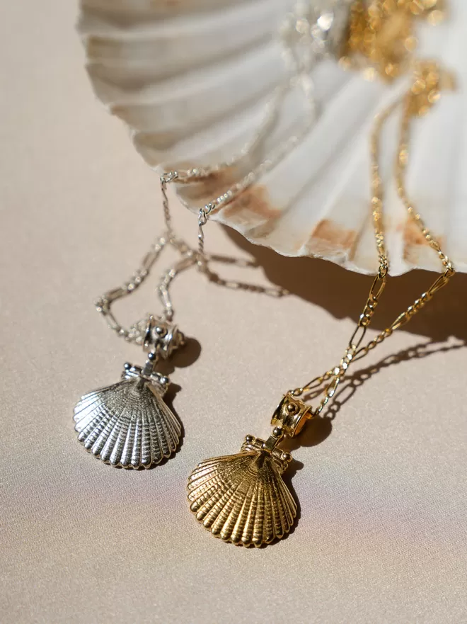 Gold vermeil and silver Finders Keepers shell pendants photographed on pale background with shell