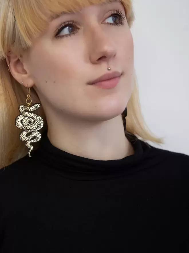large gold & black serpent earrings on blonde model