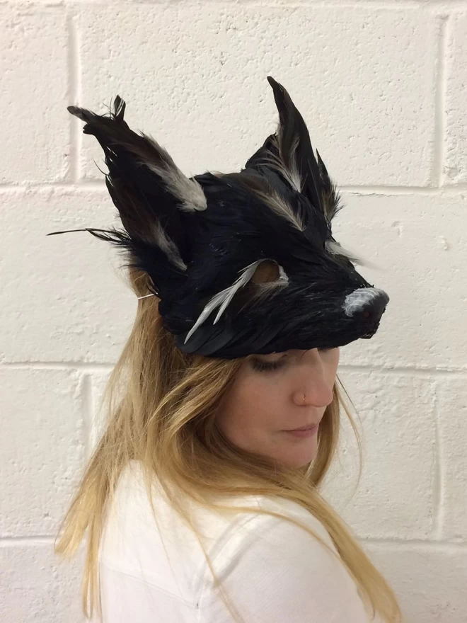 A woman wearing a luxury black fox party mask atop her head as a headdress