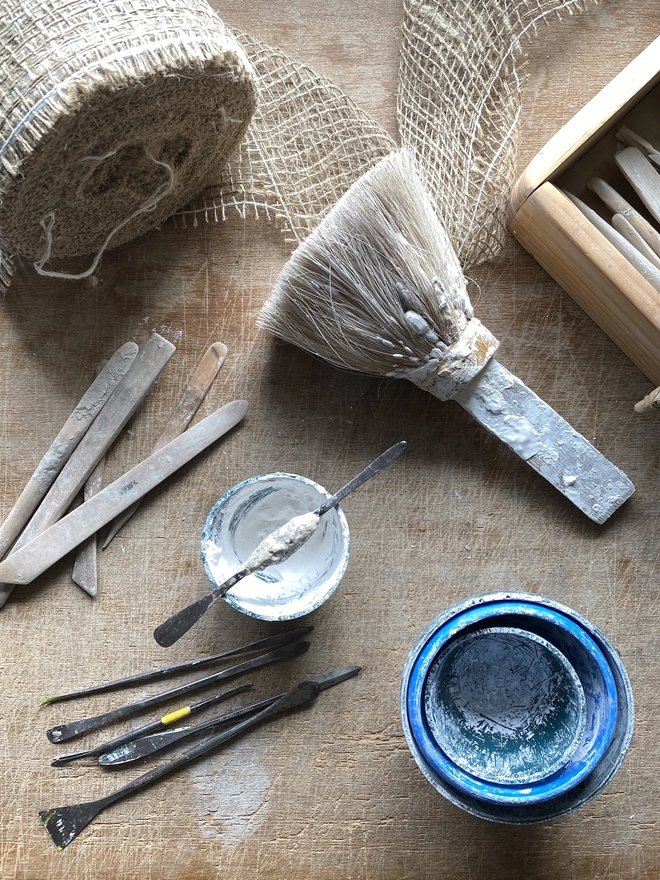 Clay modelling tools and plaster materials on a wooden bench