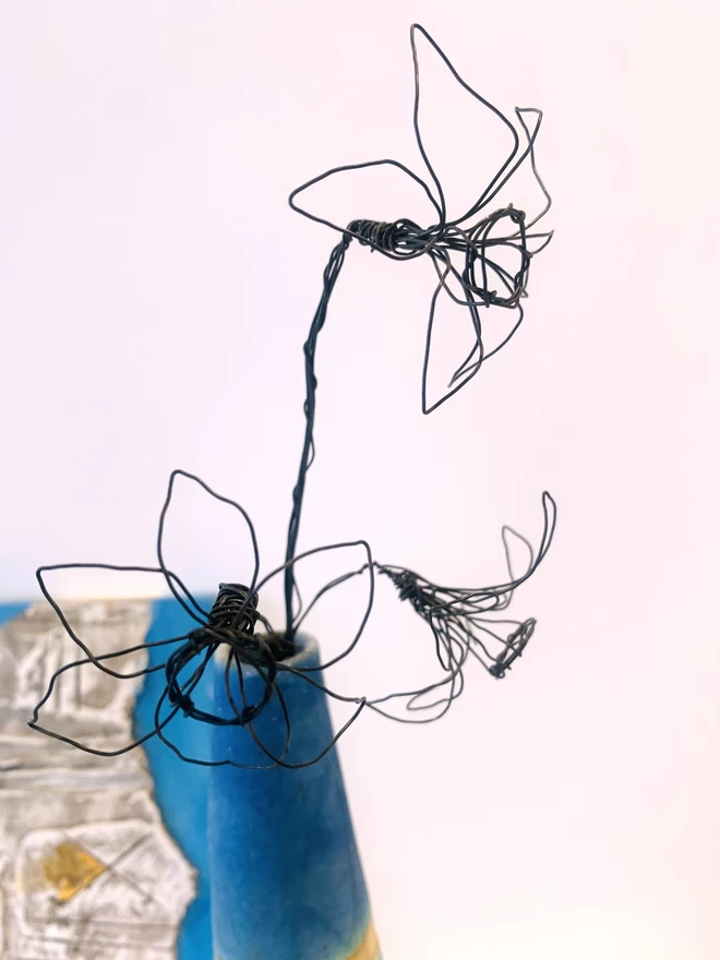 wire sculpture of a tete a tete with three flowers on the stem