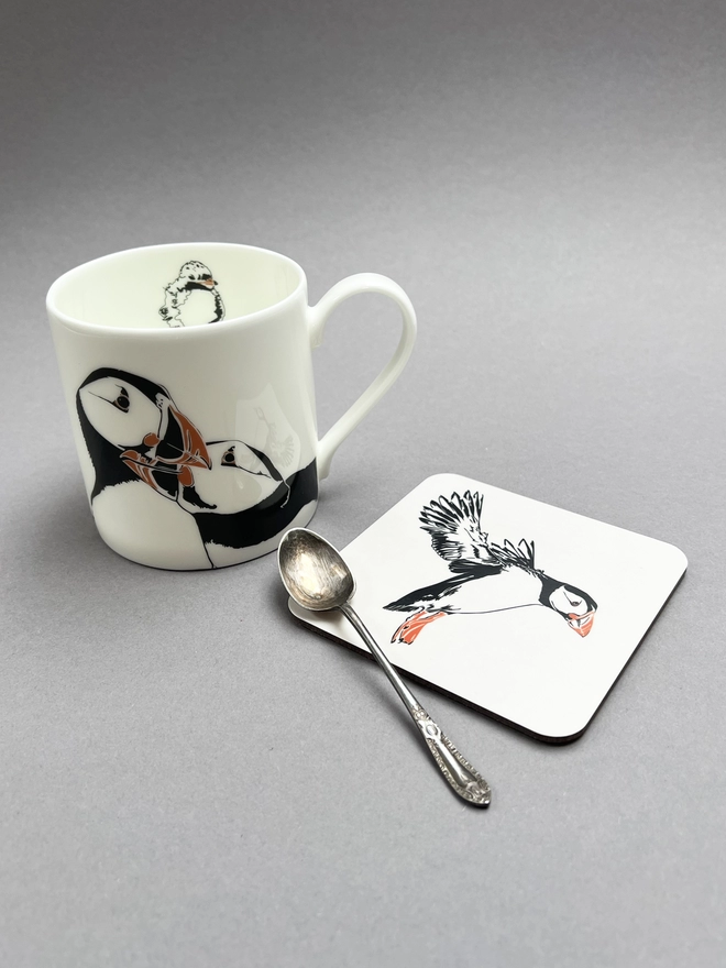 Our puffins nuzzling on a ceramin mug and our puffin landing on a coaster