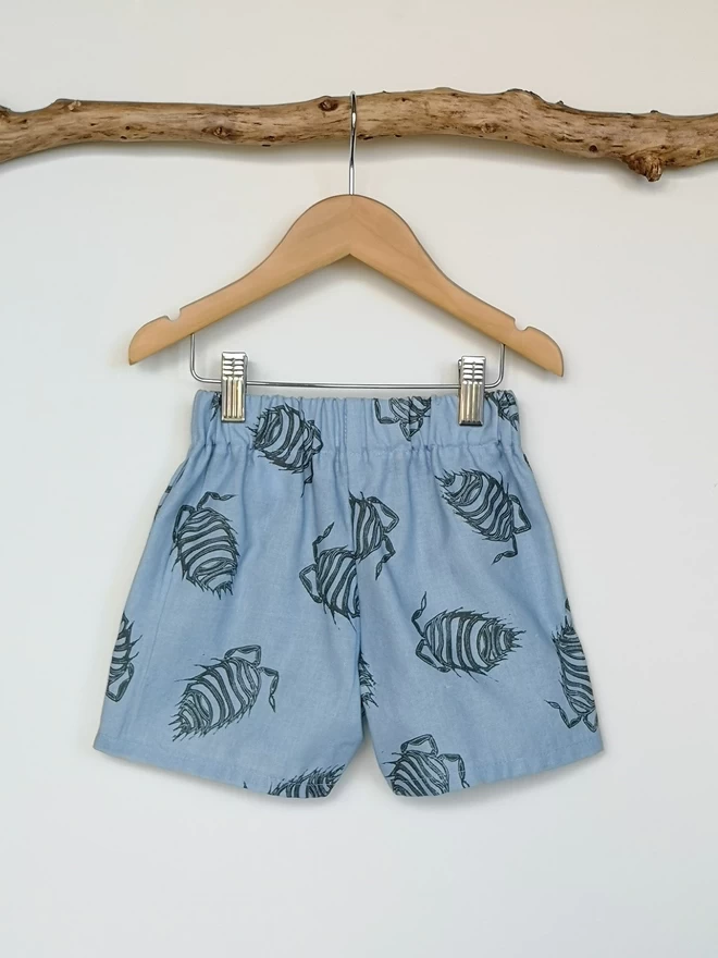 Soft Blue cotton linen lightweight unisex childrens shorts. Featuring a delicate grey woodlouse print. Simple design with elasticated waist and side seam pockets. 