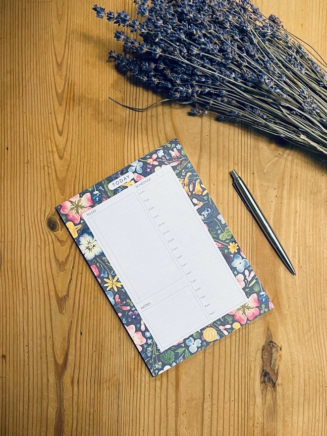 A daily planner pad with 52 tearable sheets with a nature-inspired pressed flower design
