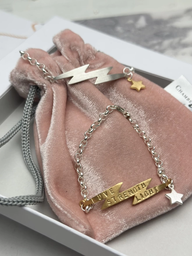 personalised gold electric bolt bracelet on sterling silver chain with silver mini star charm and sterling silver electric, lightning bolt charm bracelet on silver belcher chain with small gold plate mini star charm. gift box and pouch