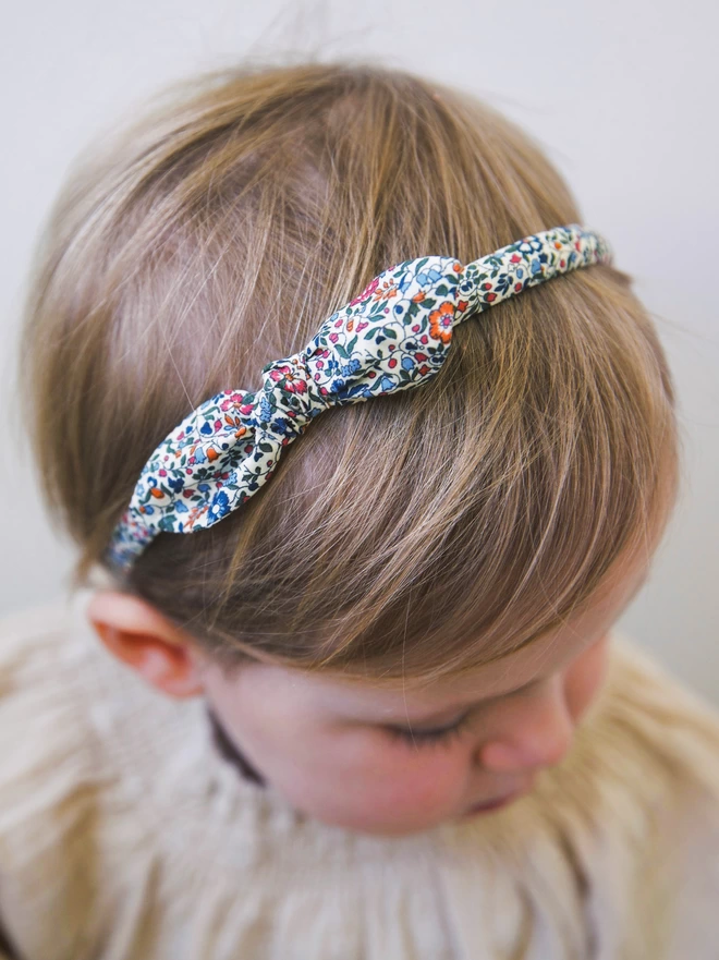 Little girl in her liberty of london Alice Band with a small side bow