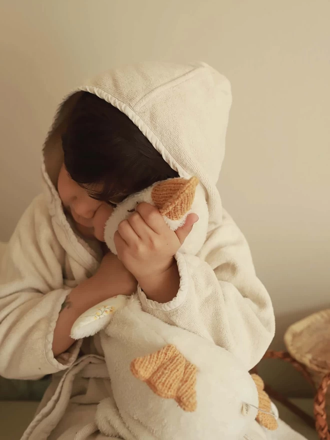 A boy on towelling robe playing with a plush duck
