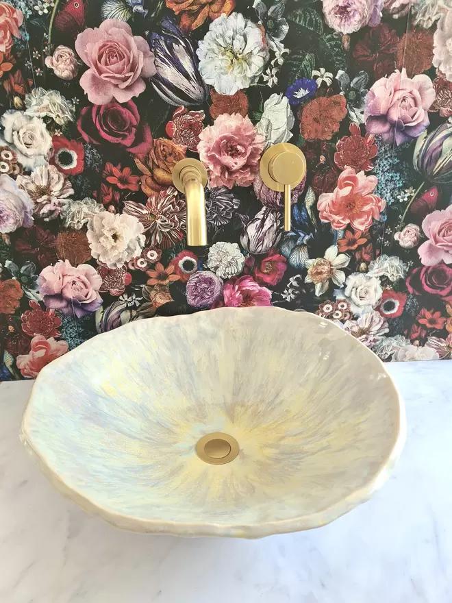 Ceramic bathroom basin, hand-crafted basin, sink, wc, bathroom, ensuite, modern bathroom, photographed against colourful floral wallpaper with gold taps, top front view