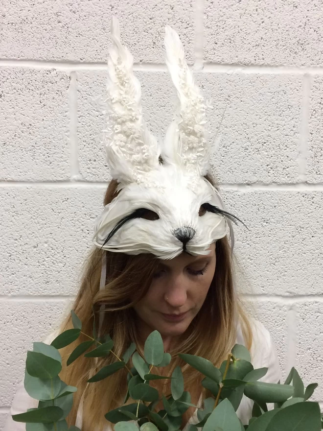 Woman wearing luxury embellished white rabbit masquerade mask atop her head as a headdress