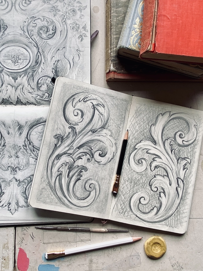 Sketchbooks with pencil drawings of acanthus leaves and drawing equipment
