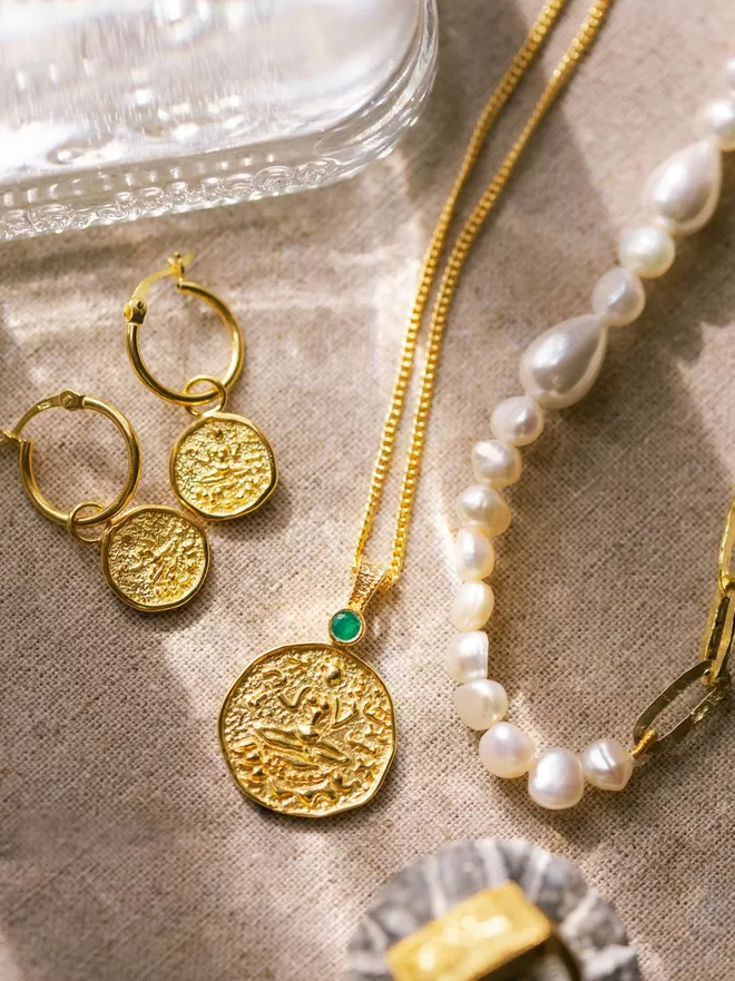 Lakshmi coin pendant with matching earrings and pearl necklace in sunlight