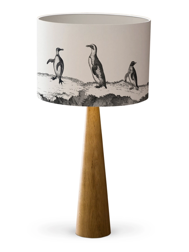Drum Lampshade featuring a parade of penguins with a white inner on a wooden base 
