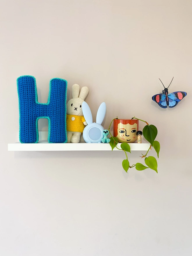 Crochet Cushion shaped like an H in Light Blue & Teal, on child's shelf