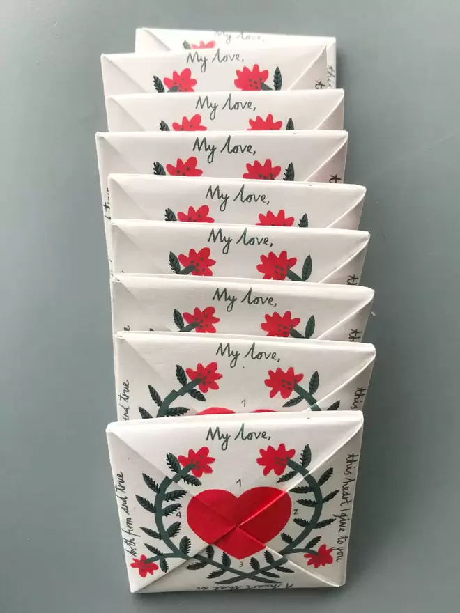 9 folded origami puzzle purses sit in a line showing the words 'my love' above hearts and flowers 