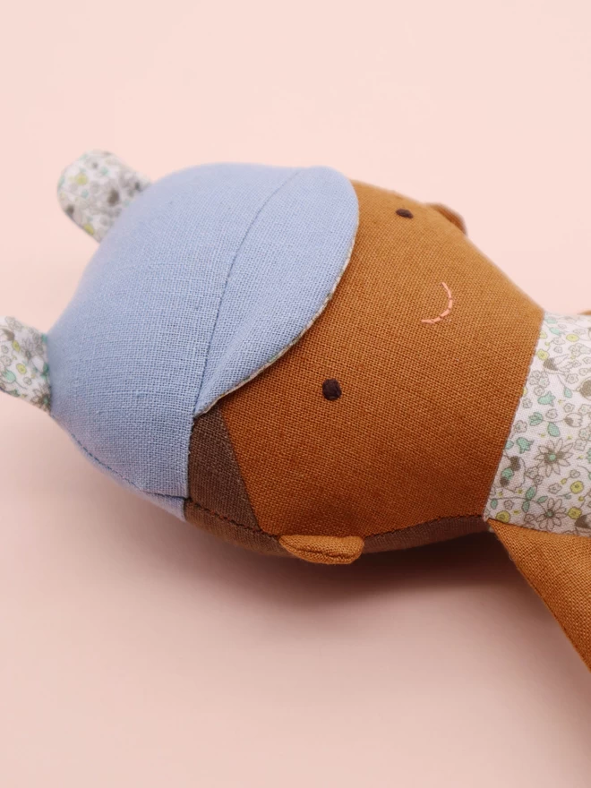 Brown skin fabric doll wearing blue cap with bear ears