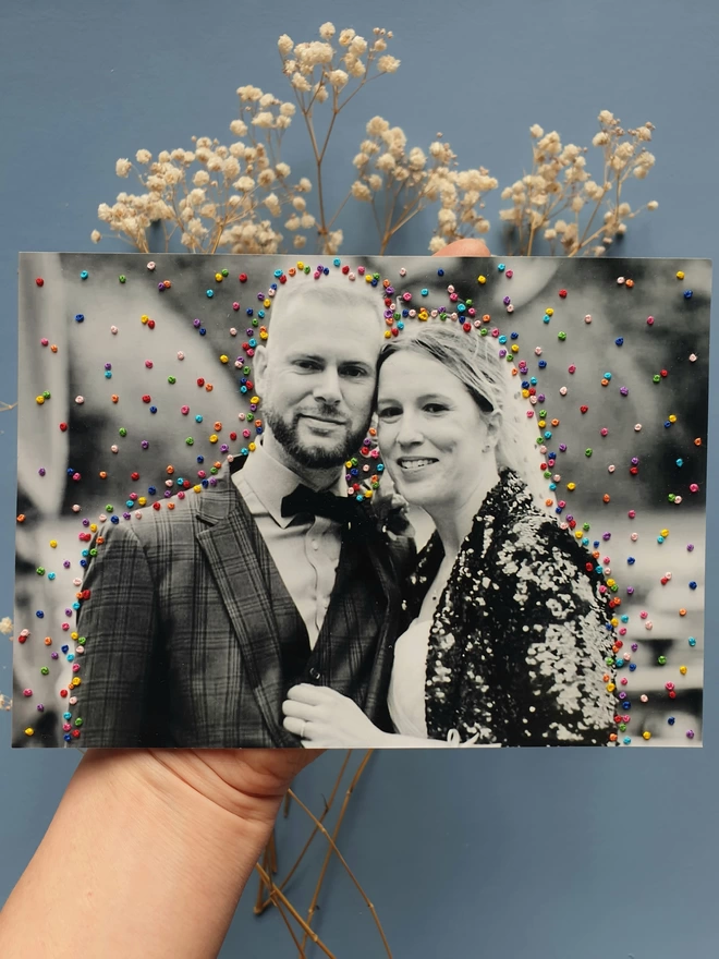  Wedding photo in B&W with hand embroidered french knot confetti held against blue background