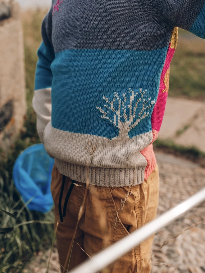 A close up of a tree detail knitted into the little boy jumper by The Faraway Gang.
