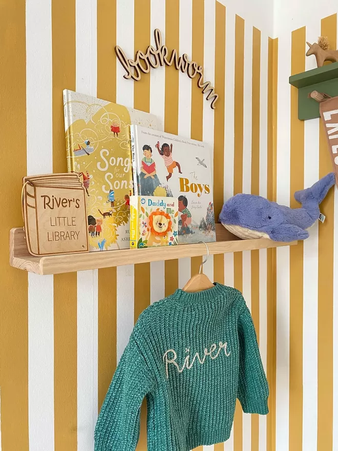 A fun stripy yellow kids room. A beautiful solid wood book and picture ledge shelf is styled up with kids books, teddies and children's decor 